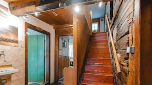 Un escalier en bois menant à un deuxième étage, un évier et une porte dotée d’un cadre vert.