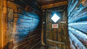 Un couloir intérieur en bois, avec une porte marquée du mot « SORTIE » et un luminaire en forme de losange au-dessus.