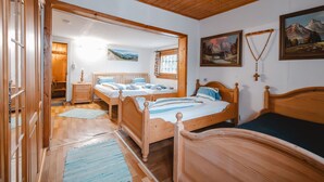 Une chambre avec un plancher en bois, deux lits, une armoire en bois et un tableau accroché au mur.