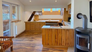 A modern kitchen with wooden cabinets, a central island, a built-in stove, and a dining area with a bench. - Apartment Daniel by Interhome (Mittersill)