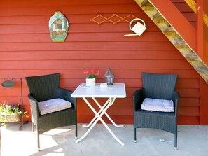 A red exterior wall with two wicker chairs and a small table with a potted plant and a lantern. - Målsnes by Interhome (Balestrand)