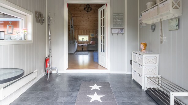 A hallway with a wooden ceiling, a chandelier, a window with a view, a door leading to a living area, and a wall with a family rules sign. - Rødehuset by Interhome (Reksteren)