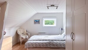 A bedroom with a bed, a chair, a dresser, a window, and a picture on the wall. - Rødehuset by Interhome (Reksteren)