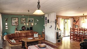 A cozy living room with a brown leather sofa, a wooden coffee table, and a dining area with a table set for four. - Gule huset by Interhome (Reksteren)
