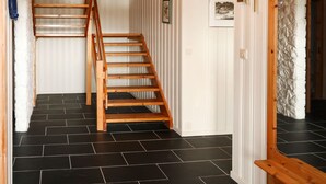 A wooden staircase leading to a room with white paneled walls and black tiled flooring. - Gule huset by Interhome (Reksteren)