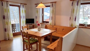 A dining area with a wooden table, chairs, a bench, and a TV.