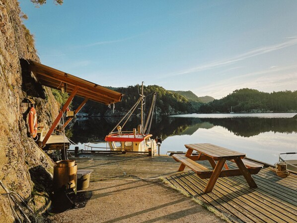 A dock with a wooden boat, a picnic table, and a lifebuoy.