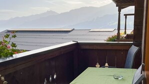 A wooden deck with a table and chairs, overlooking a mountainous landscape. - Bauernhof Gasteg (L) by Interhome (Kaprun)