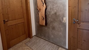 A hallway with two wooden doors, a textured gray wall, and a wooden wall art piece. - Bauernhof Gasteg (L) by Interhome (Kaprun)