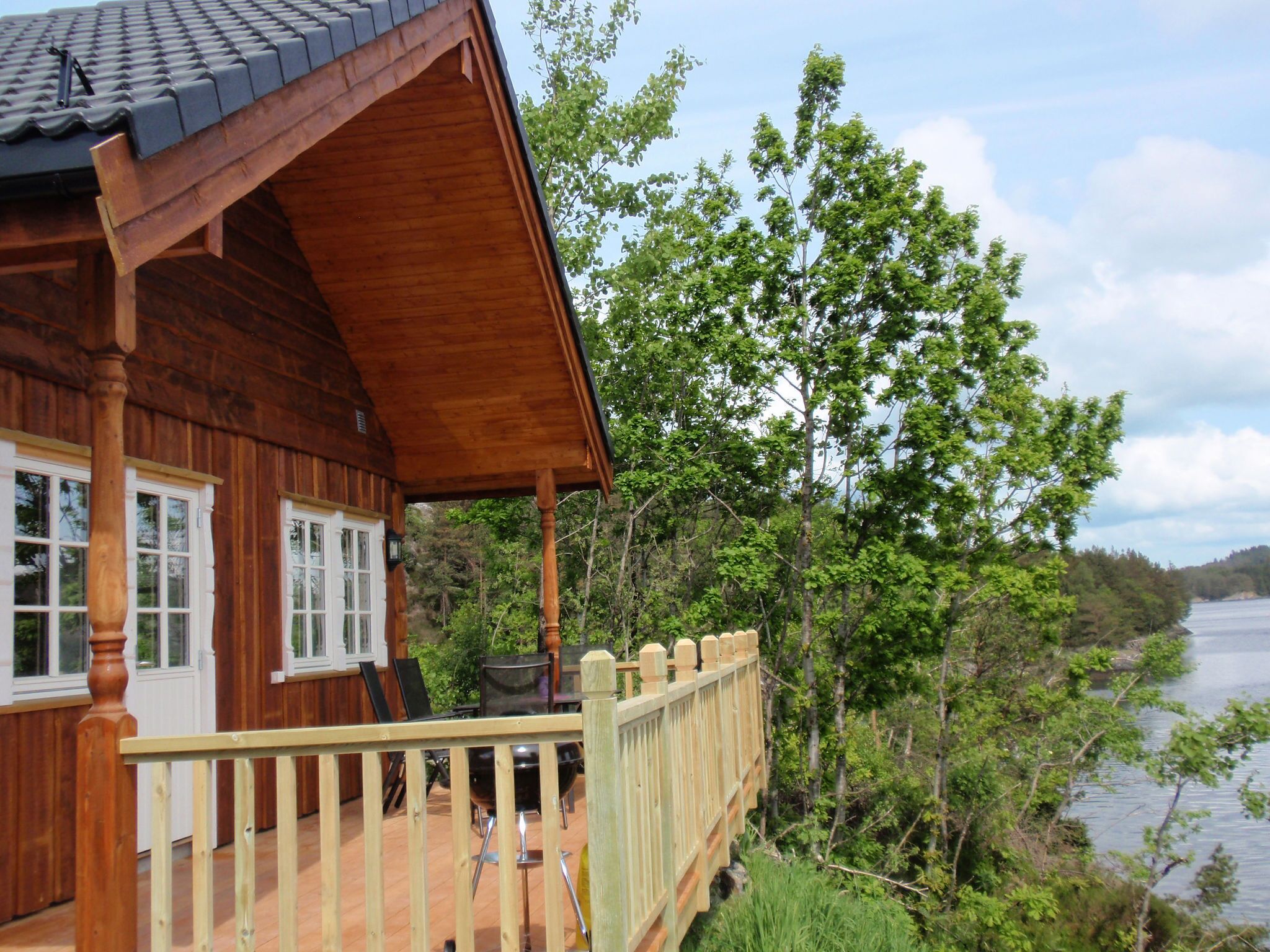 Une cabane en bois dotée d’un porche couvert, d’une terrasse et offrant une vue sur un lac.