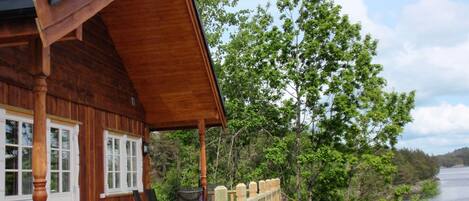 Une cabane en bois dotée d’un porche couvert, d’une terrasse et offrant une vue sur un lac.