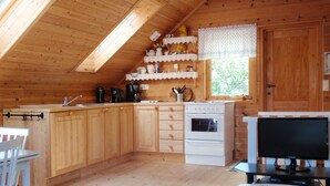 A cozy kitchen with wooden cabinets, a white stove, and a dining table with a candle. - Vacation home Tufto by Interhome (Lundegrend)