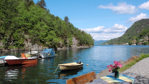 A calm lake with boats docked on the shore, surrounded by lush greenery and hills. - Vacation home Tufto by Interhome (Lundegrend)