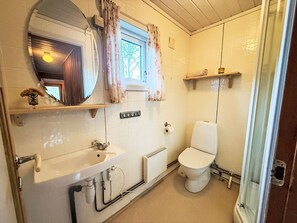 A bathroom with a white sink, a toilet, a mirror, and a window with floral curtains.