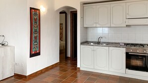 Une cuisine avec des armoires blanches, un évier en acier inoxydable et une cuisinière.