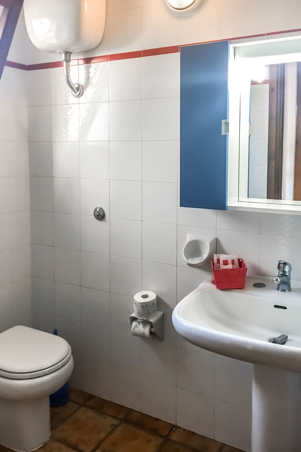 Een badkamer met toilet, wastafel, spiegel en een toiletrolhouder aan de muur.