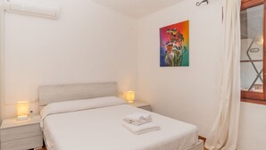Une chambre à coucher avec un lit, des tables de chevet, un tableau et une fenêtre avec des rideaux.