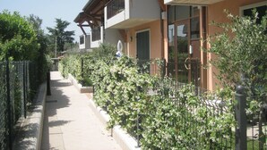 A multi-story building with balconies, a gated pathway, and lush greenery. - La Madonnina by Interhome (Lazise)