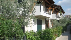 A multi-story residential building with balconies, surrounded by lush greenery. - La Madonnina by Interhome (Lazise)