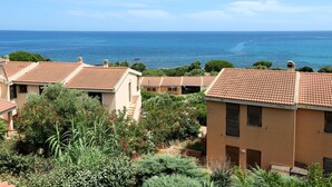 A coastal residential area with terracotta-roofed houses, lush greenery, and a view of the sea. - Su Tramatzu (PCR105) by Interhome (Porto Corallo)
