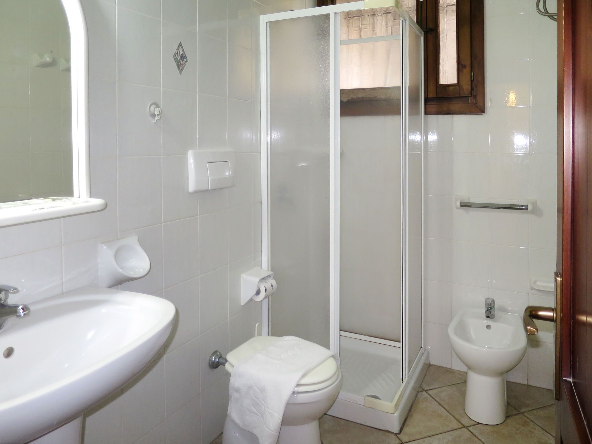A bathroom with a sink, toilet, bidet, and a glass-enclosed shower.