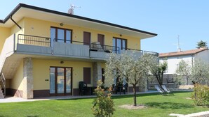 A two-story building with a balcony, a stone wall, and a well-maintained lawn.