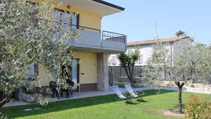 A two-story building with a balcony, a small garden with a lawn, and a tree. - Corte Chiara by Interhome (Lazise)