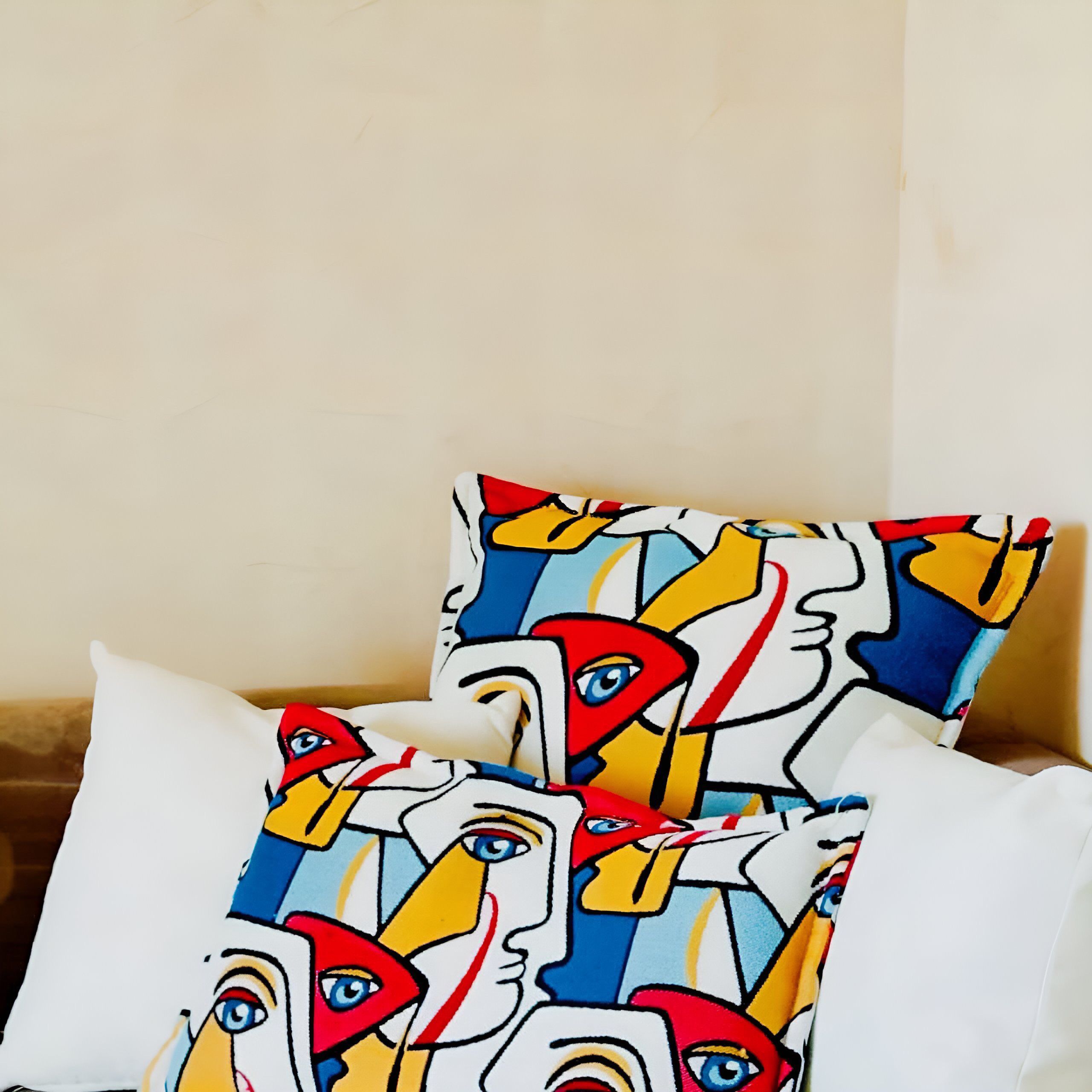 A bed with two pillows featuring a colorful abstract pattern.
