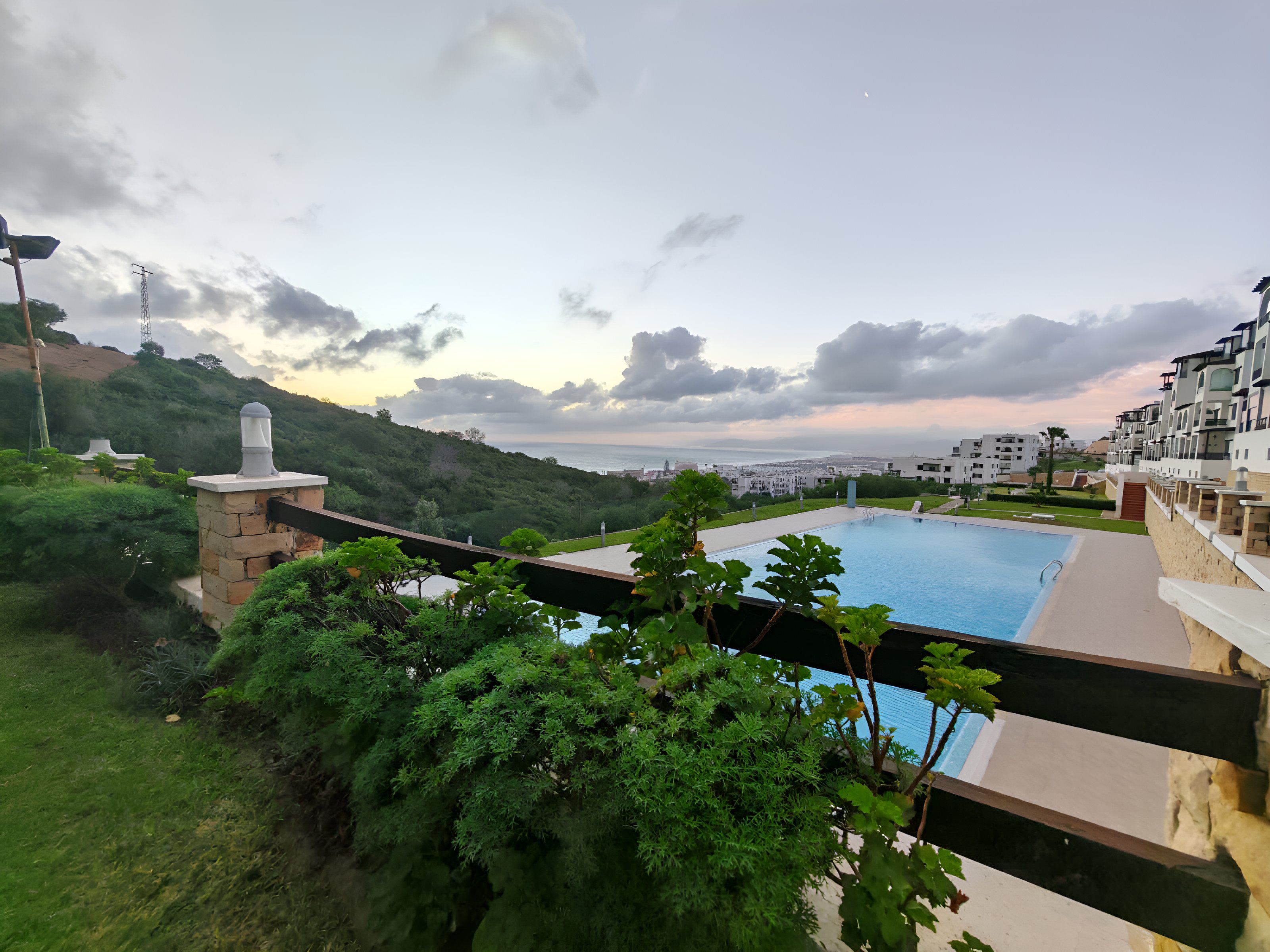 A swimming pool with a view of a cityscape and hills in the background.