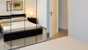 Une chambre à coucher comprenant un lit, une table de chevet, une lampe et une porte donnant sur une autre pièce.