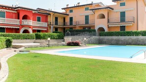 A residential building with a swimming pool, balconies, and a stone wall. - Lady Anna by Interhome (Lazise)