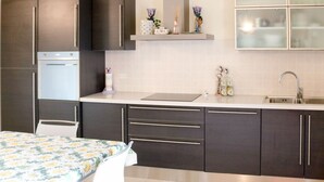 A modern kitchen with dark cabinets, a built-in oven, a sink, and a countertop. - Lady Anna by Interhome (Lazise)