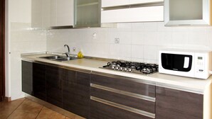Eine moderne Küche mit Gasherd, Mikrowelle, Spüle und dunklen Holzschränken.