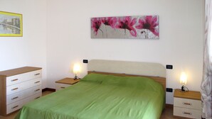 Ein Schlafzimmer mit einem Bett, zwei Nachttischen, einer Kommode und einem Bild an der Wand.