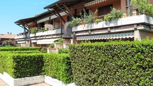 A traditional chalet with multiple balconies, a tiled roof, and a well-maintained hedge in the foreground. - La Casara B by Interhome (Lazise)