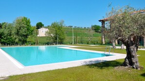 A rectangular swimming pool with a clear blue water surface, surrounded by a grassy area and a stone building in the background. - I Molini by Interhome (Lazise)