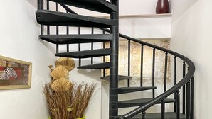 A spiral staircase with black railings and a green vase with dried plants on the left. - Casa Maja by Interhome (Roccascalegna)