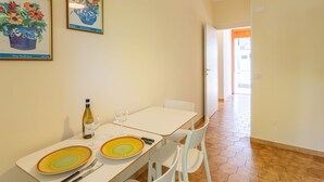 A dining area with a table set for two, a bottle of wine, and two wine glasses. There are framed botanical prints on the wall.