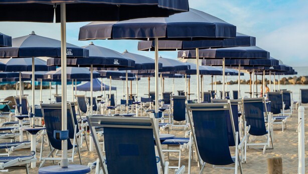 Rows of beach chairs and umbrellas on a sandy beach.