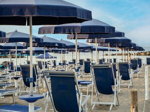 Rows of beach chairs and umbrellas on a sandy beach.