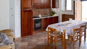 A kitchen with wooden cabinets, a stove, and a dining table with chairs.