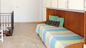A small, clean room with a bed, a desk, and a chair.