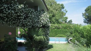 A residential property with a swimming pool, lush greenery, and a stone pathway leading to the pool. - Vacation home Serena by Interhome (Lazise)