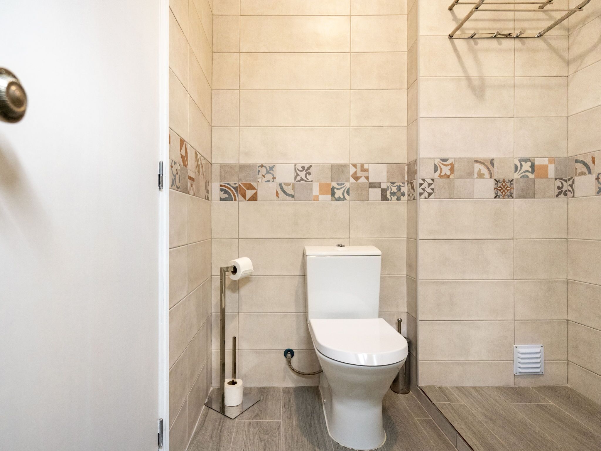 A bathroom with a toilet, a roll of toilet paper, and a shower area.