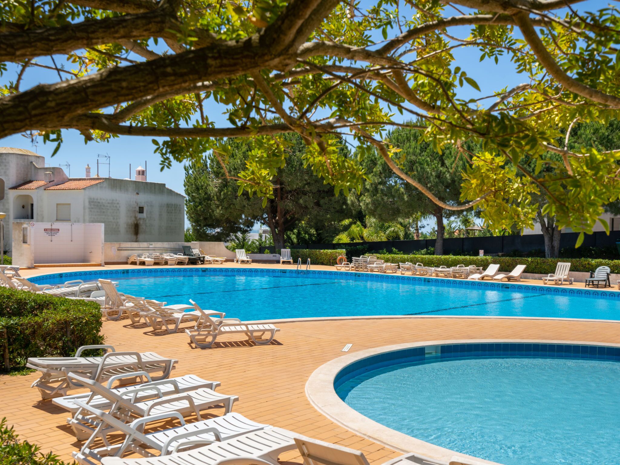 Una piscina con lettini e un edificio sullo sfondo.
