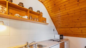 Een keuken met een dubbele spoelbak, houten keukenkastjes, een magnetron en een vaatwasser.