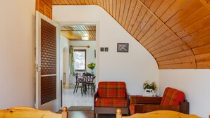 Een gezellige kamer met houten meubels, een eethoek met een tafel en stoelen, en een zicht op een andere kamer.