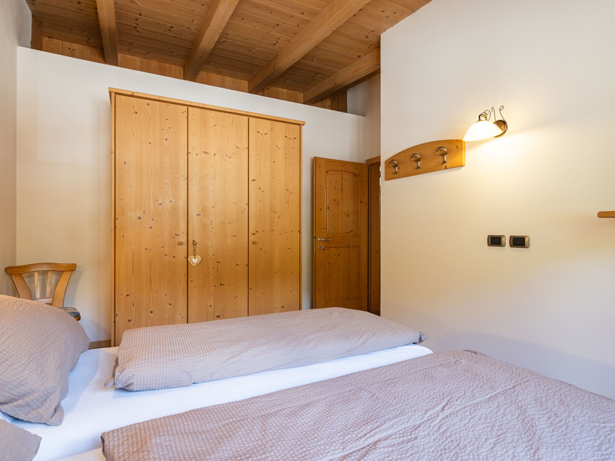 Une chambre avec des armoires en bois, un lit avec des oreillers et un luminaire fixé au mur.