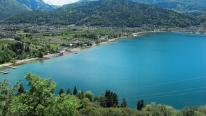 Eine Stadt am Seeufer mit einem Steg, umgeben von Bergen und viel Grün.