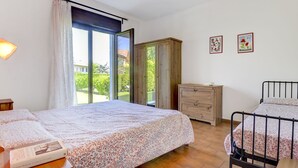 Ein Schlafzimmer mit Bett, Schminktisch, Nachttisch und einem Fenster mit Vorhängen.